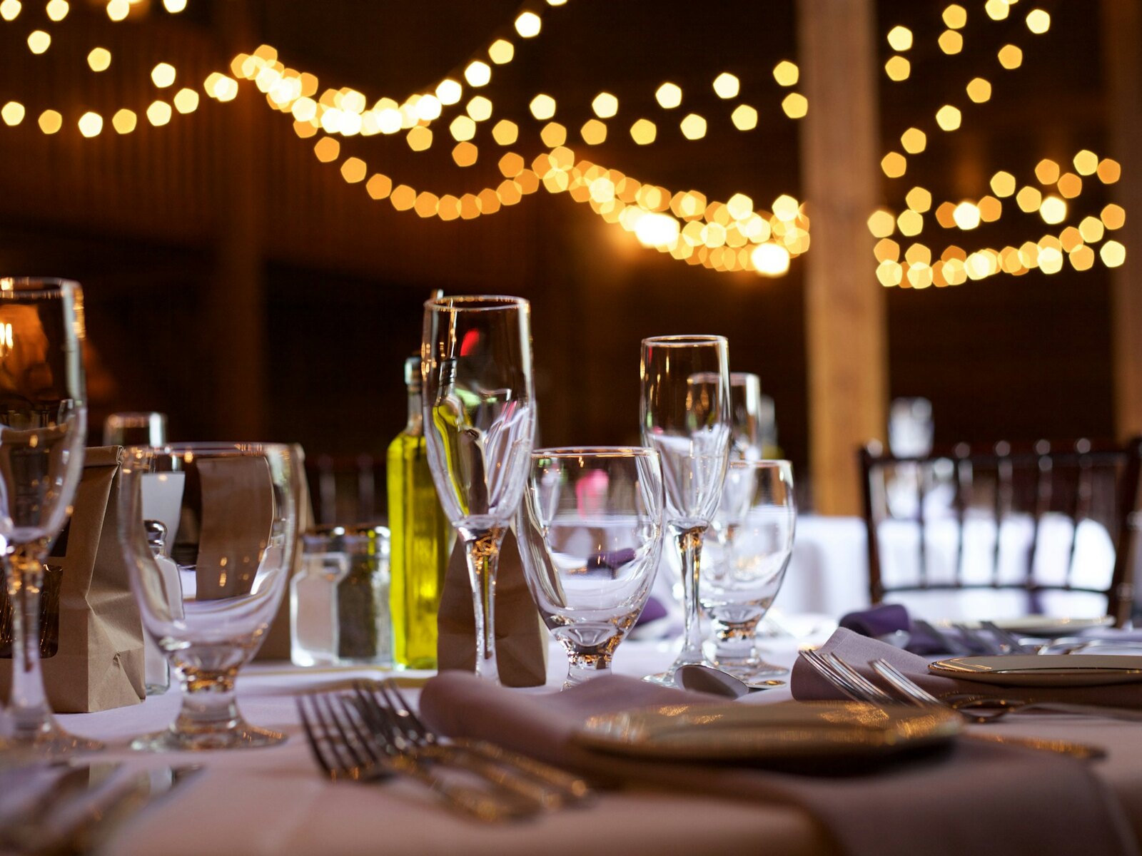 Long tables set for dinner inside a candlelit barn